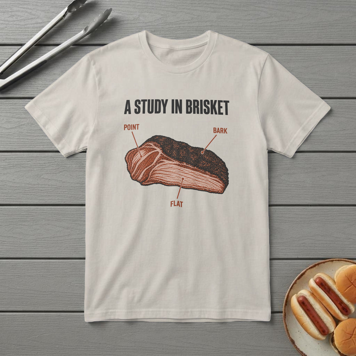Ivory t-shirt with a field-guide brisket drawing labelled point, flat and bark, titled "A Study in Brisket", on a grey deck