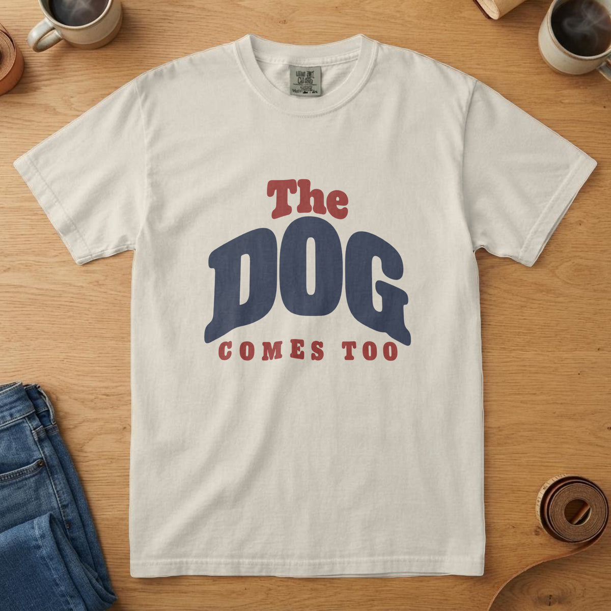 Ivory t-shirt with navy and flag red arch lettering reading "The Dog Comes Too"