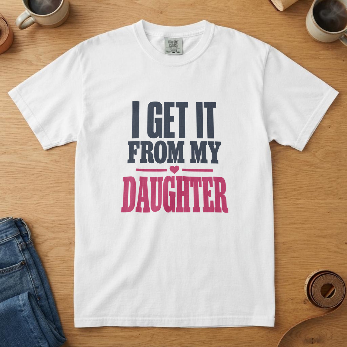 White t-shirt with navy and pink type with a small heart and the words "I Get It From My Daughter"