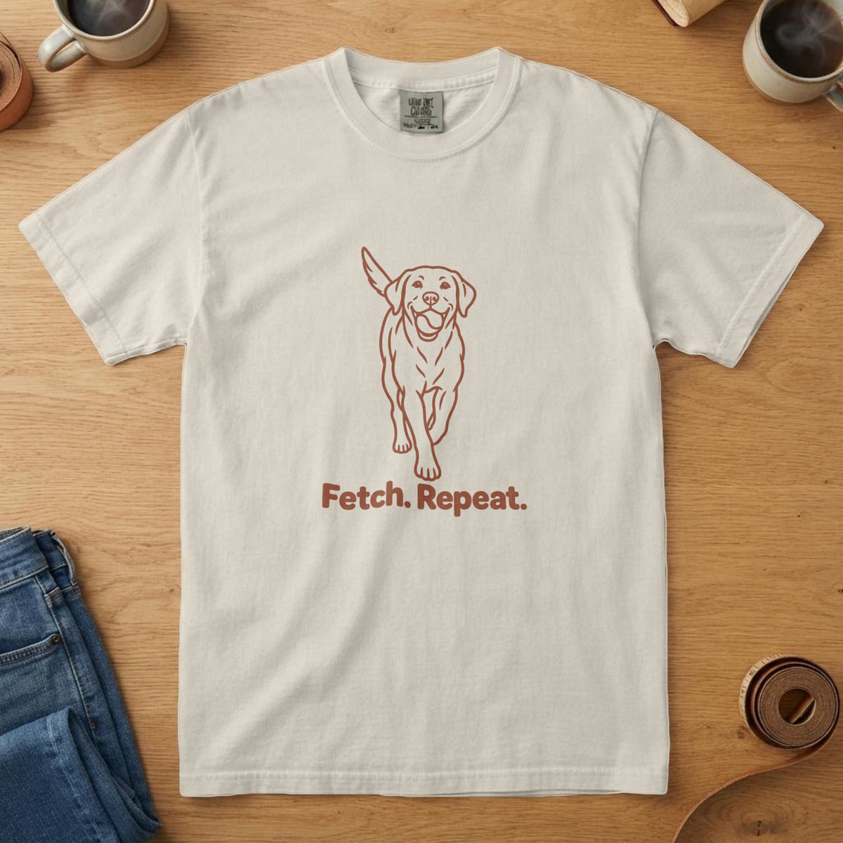 Ivory t-shirt with a rust line drawing of a dog trotting toward the viewer and the words "Fetch. Repeat."