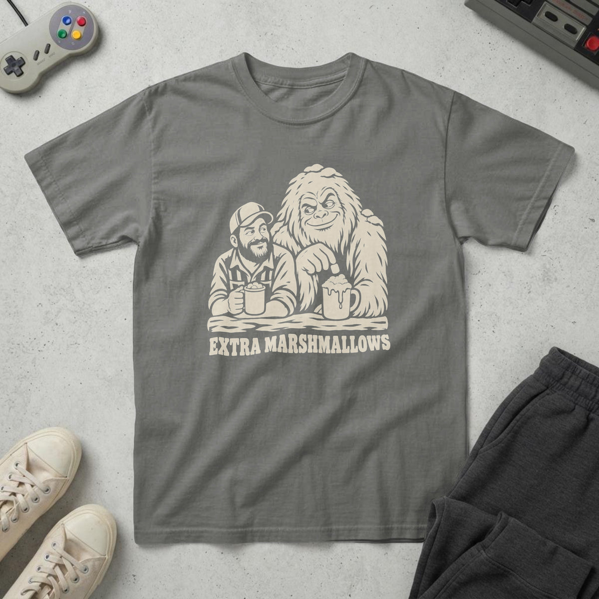 Pepper t-shirt with a woodcut of a snowy Bigfoot and a dad with hot cocoa and the words "Extra Marshmallows", on concrete