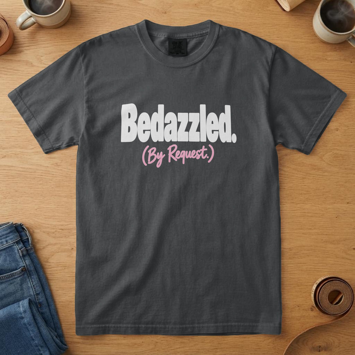 Black t-shirt with bold white type with a pink script line and the words "Bedazzled. By Request."