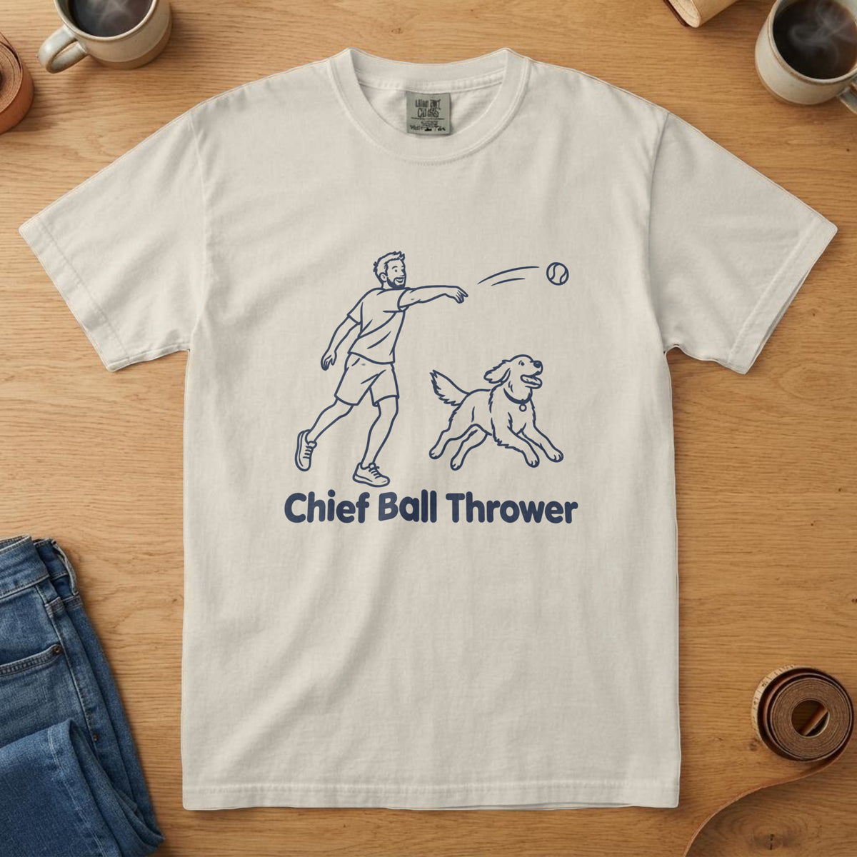 Ivory t-shirt with a navy line drawing of a man throwing a ball with a dog sprinting after it and "Chief Ball Thrower"