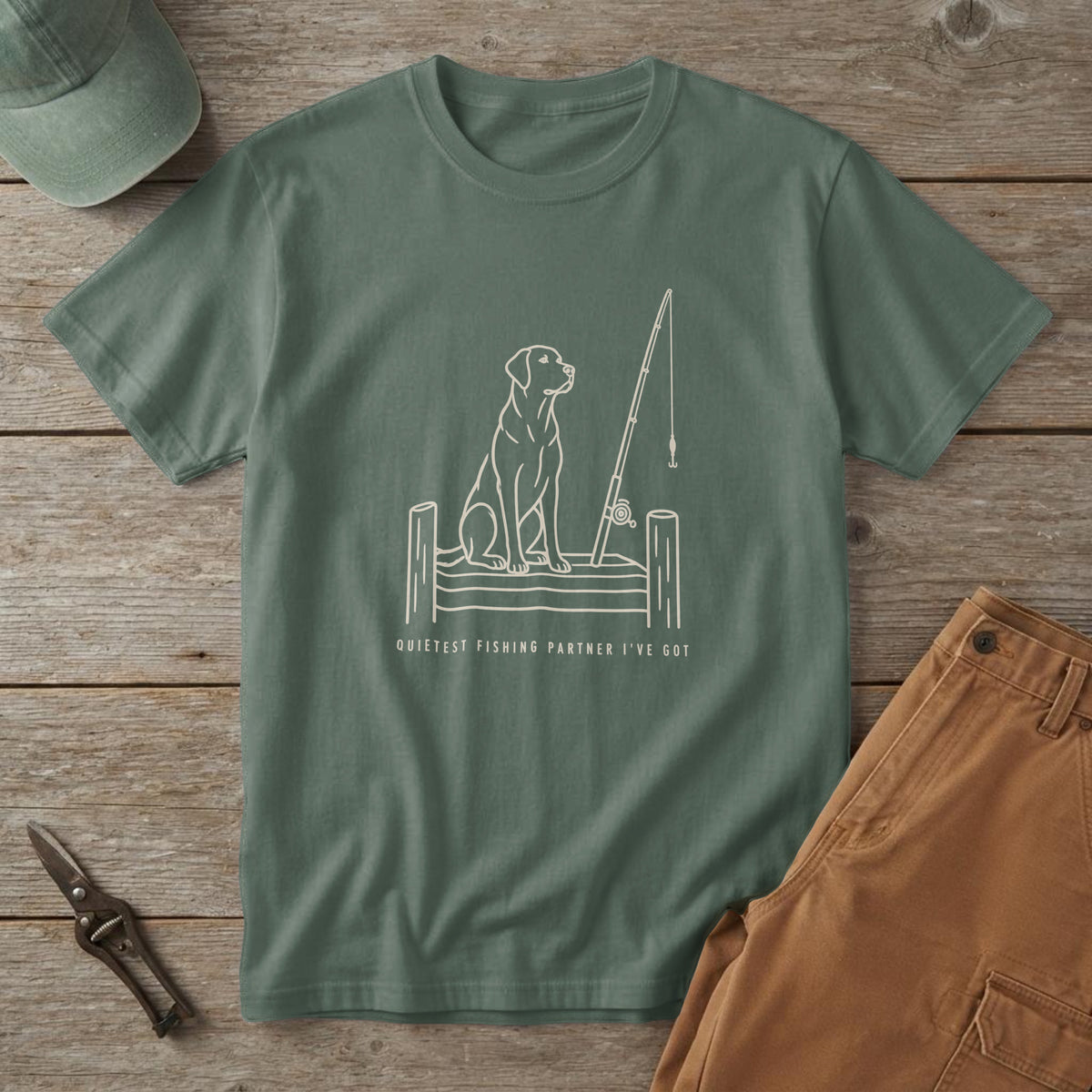 Blue Spruce t-shirt with bone ink of a dog on a dock beside a fishing rod and "Quietest Fishing Partner I've Got"