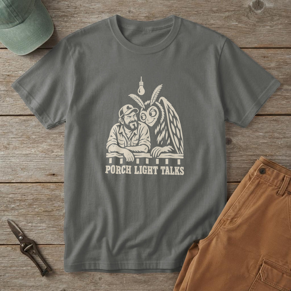Pepper t-shirt with a woodcut of Mothman and a dad at a porch rail and the words "Porch Light Talks", on a picnic table