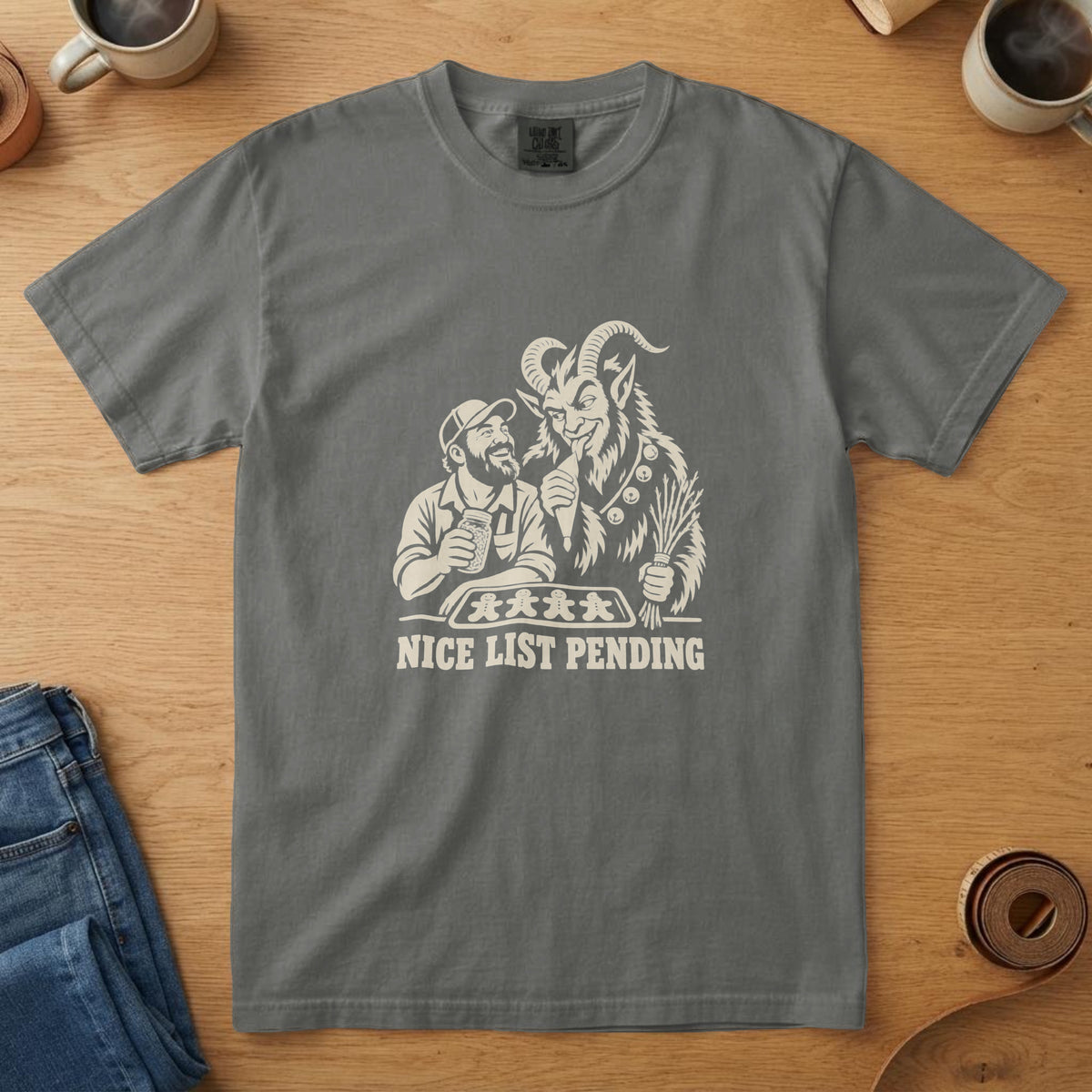 Pepper t-shirt with a woodcut of Krampus and a dad decorating gingerbread cookies and the words "Nice List Pending", on oak