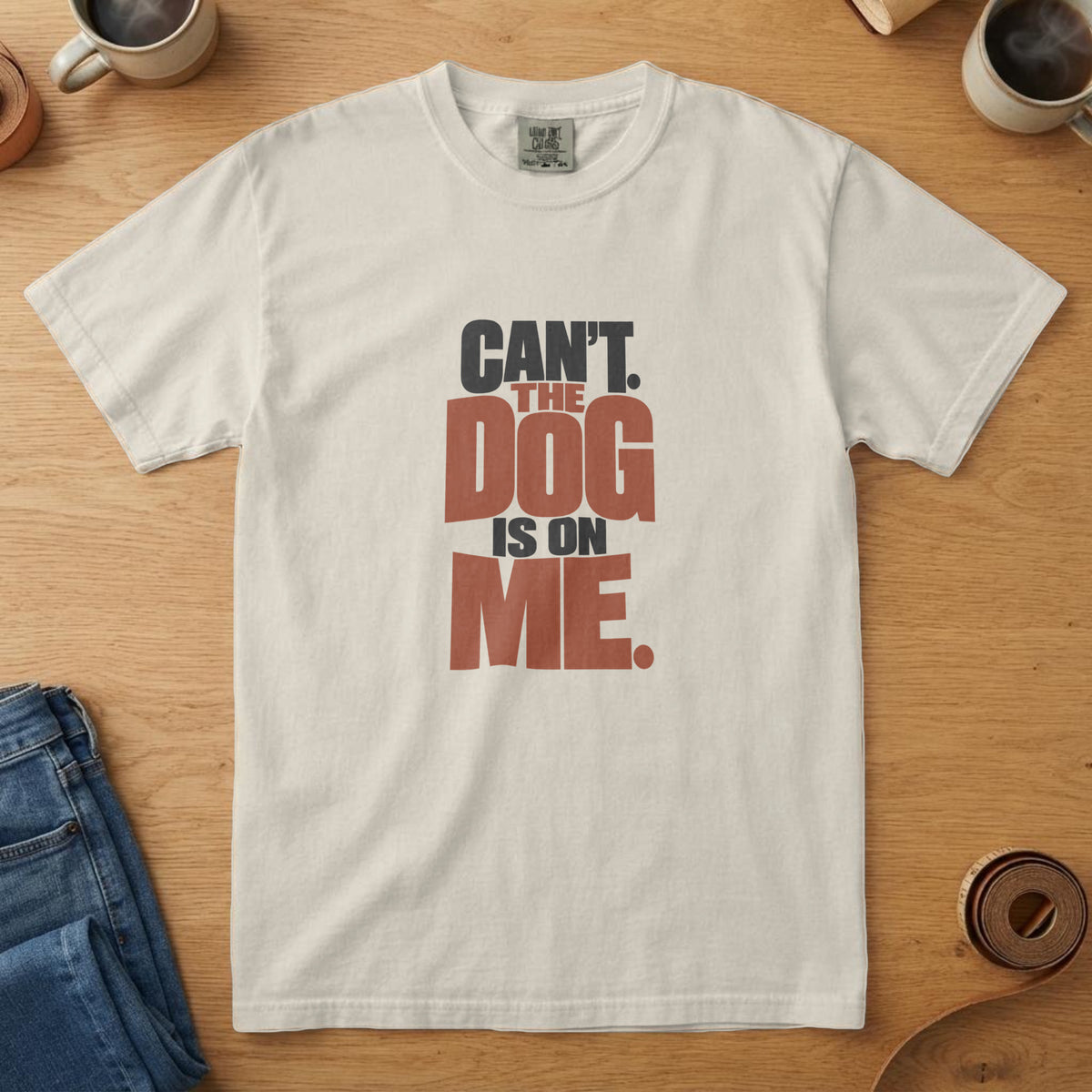 Ivory t-shirt with bold near-black and rust stacked type reading "Can't. The Dog Is On Me."